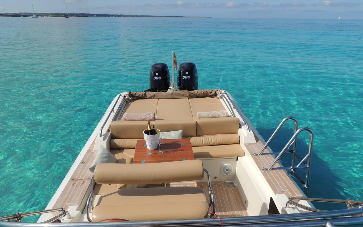 The bow of a motor boat with cushioned seats over turquoise water