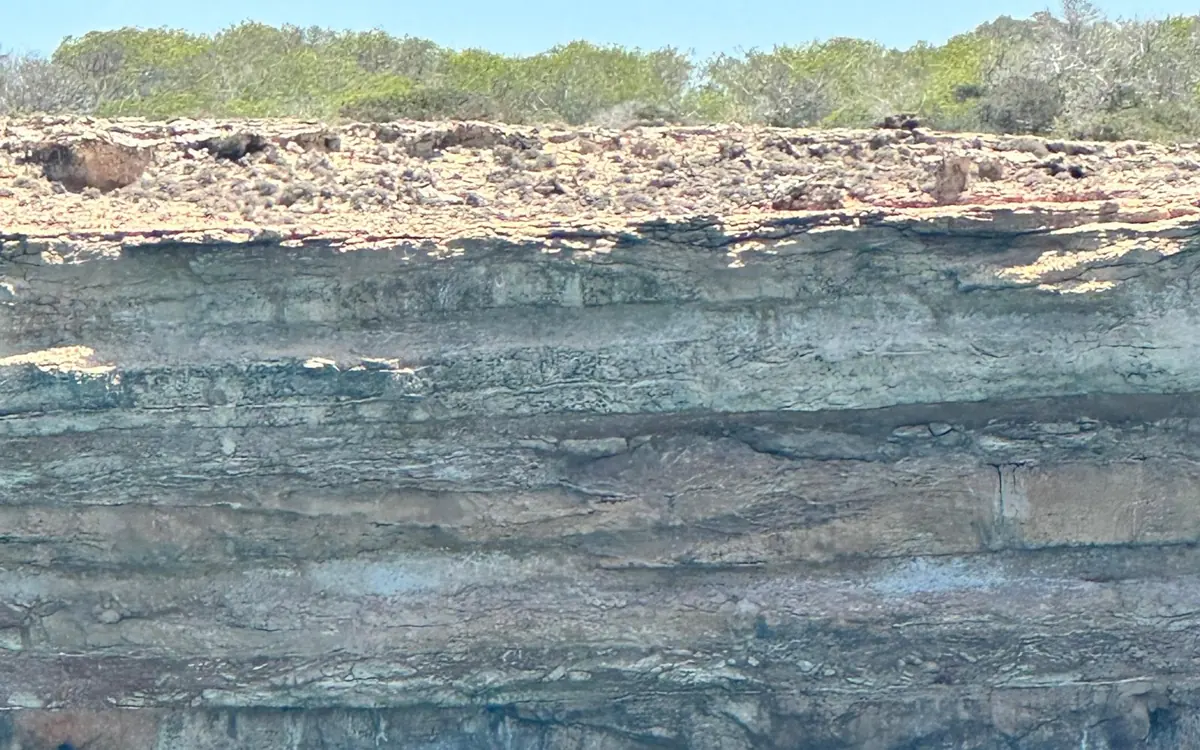 Layered limestone cliffs rising straight out of the water, seen close up