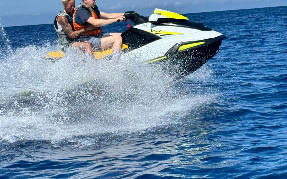 Two riders on a jet ski throwing up spray on open water