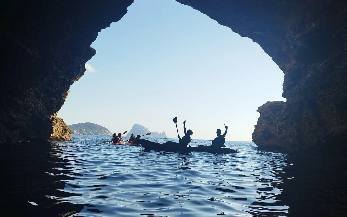 Kayakers paddling inside a sea cave towards the open water