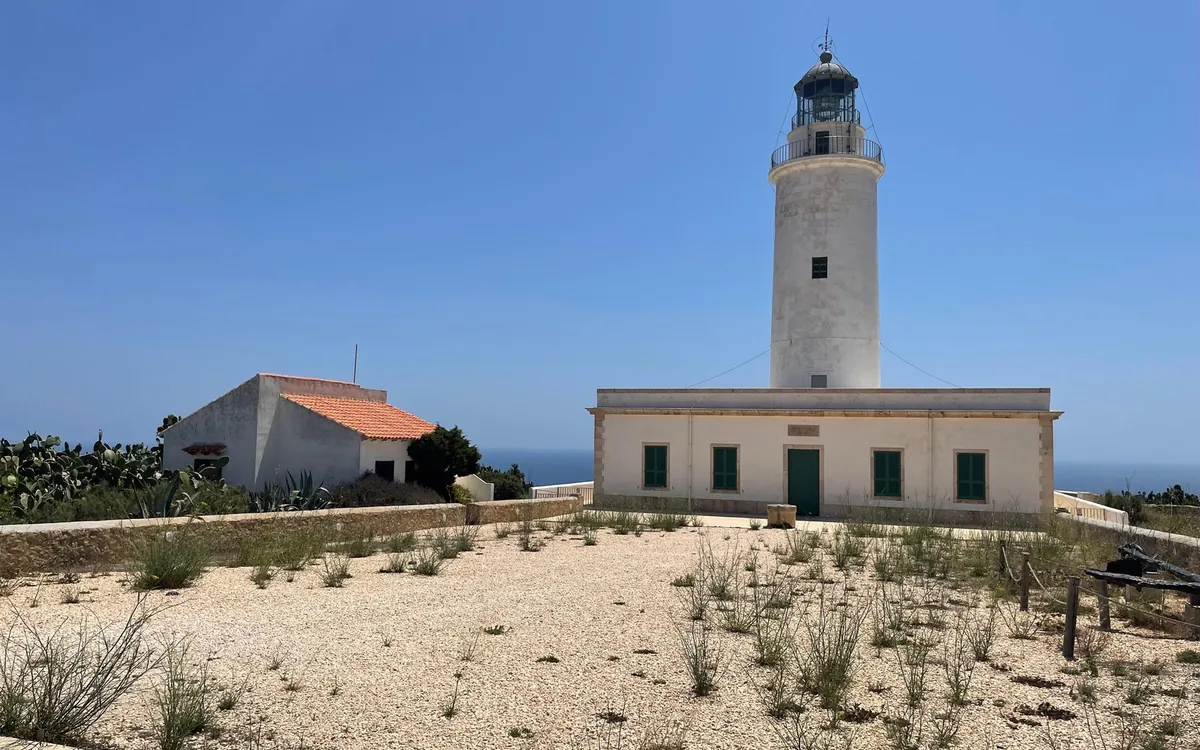 The white La Mola lighthouse and its low keeper's house on Formentera under a clear blue sky