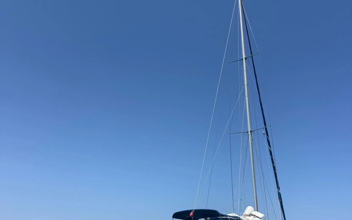 The tall mast and rigging of a sailboat against a clear blue sky